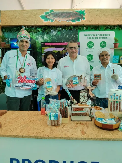 Participantes junto a una muestra de productos acuícolas en el stand.